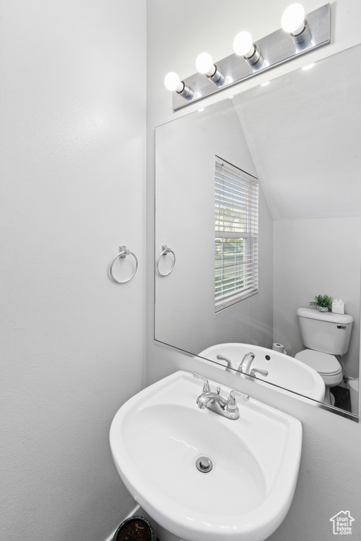 Bathroom featuring a sink, lofted ceiling, and toilet