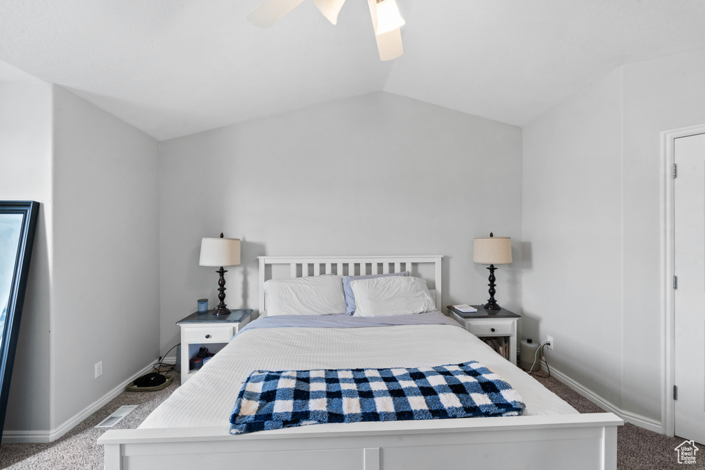 Carpeted bedroom with baseboards, vaulted ceiling, and a ceiling fan