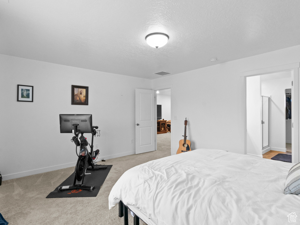Bedroom with a textured ceiling, baseboards, and light carpet