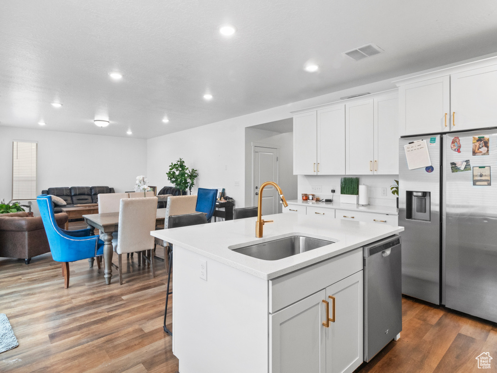 Kitchen with a sink, stainless steel appliances, recessed lighting, light countertops, and white cabinets