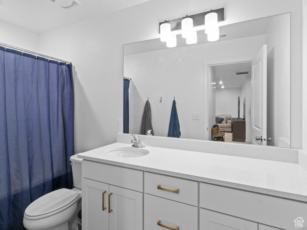 Ensuite bathroom with toilet, vanity, and a shower with shower curtain
