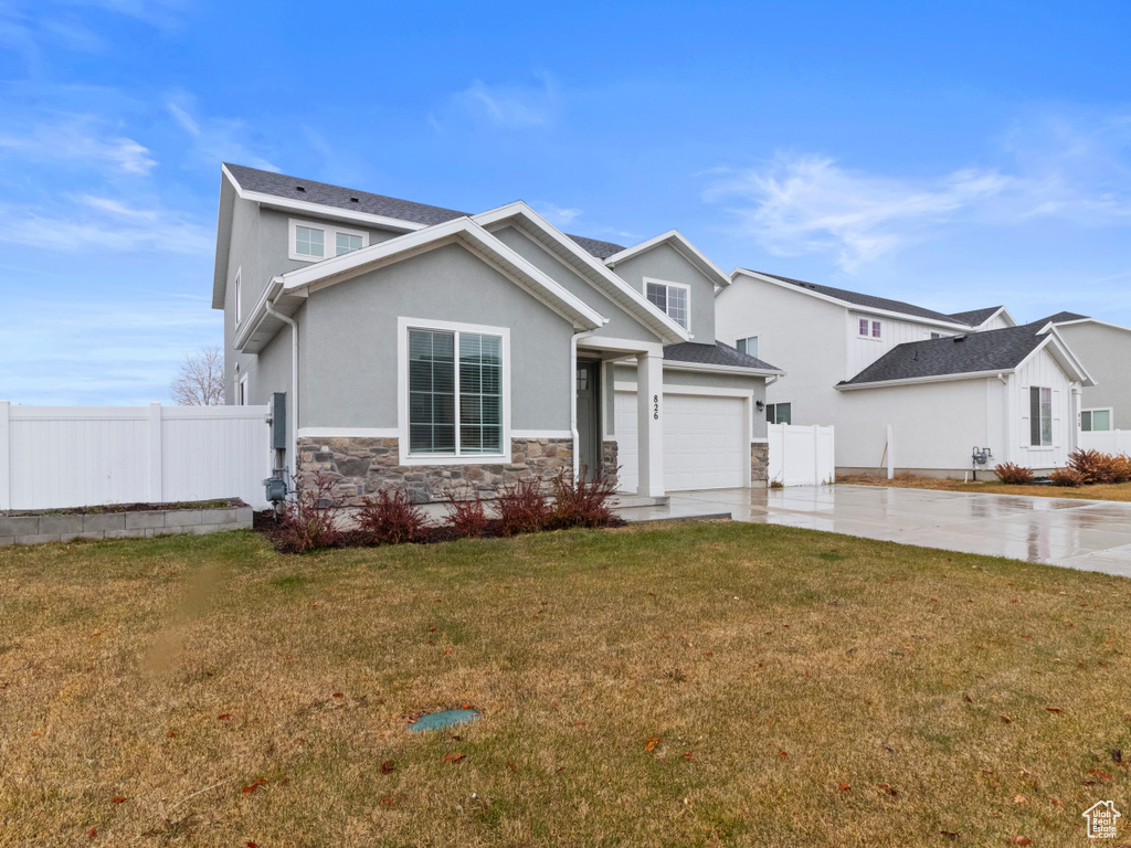 View of front of house featuring driveway, stone siding, and stucco siding