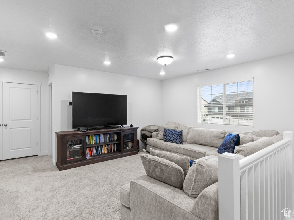 Carpeted living area with recessed lighting and a textured ceiling
