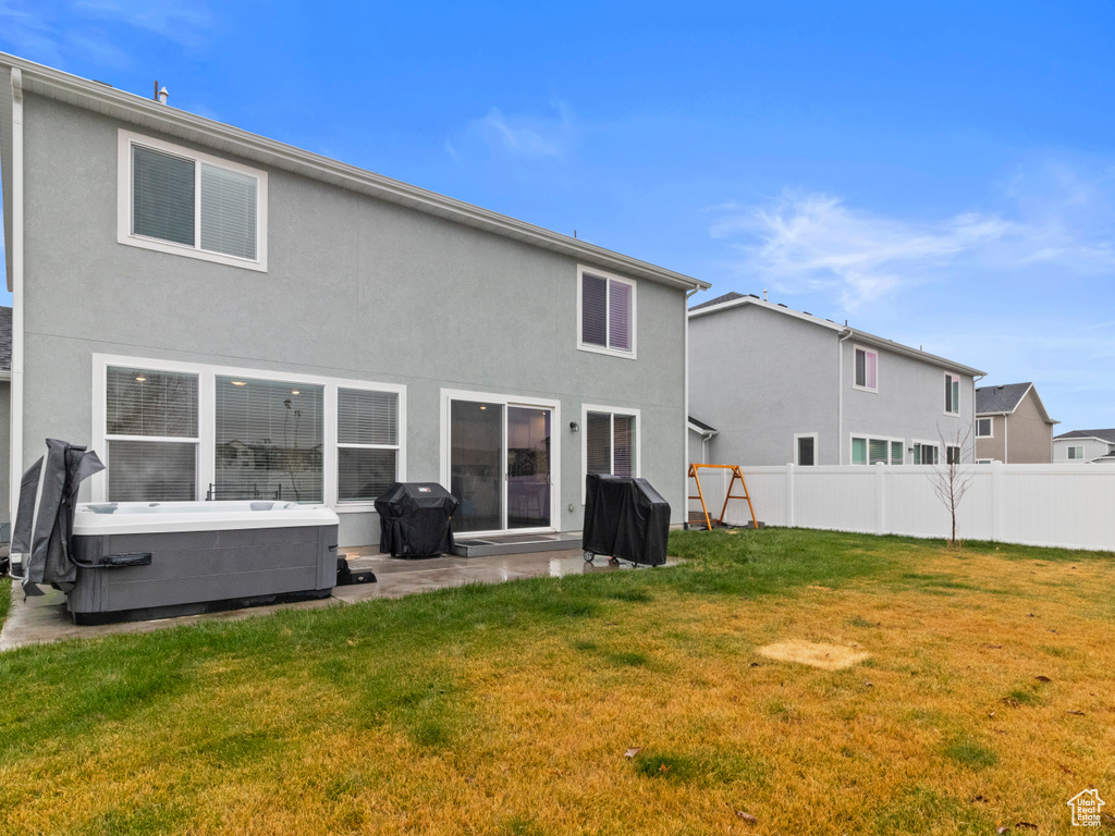 Back of house with a hot tub and stucco siding