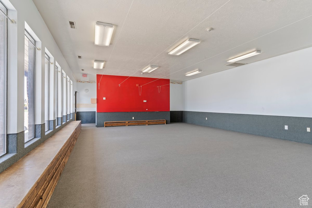 Carpeted empty room featuring a wainscoted wall