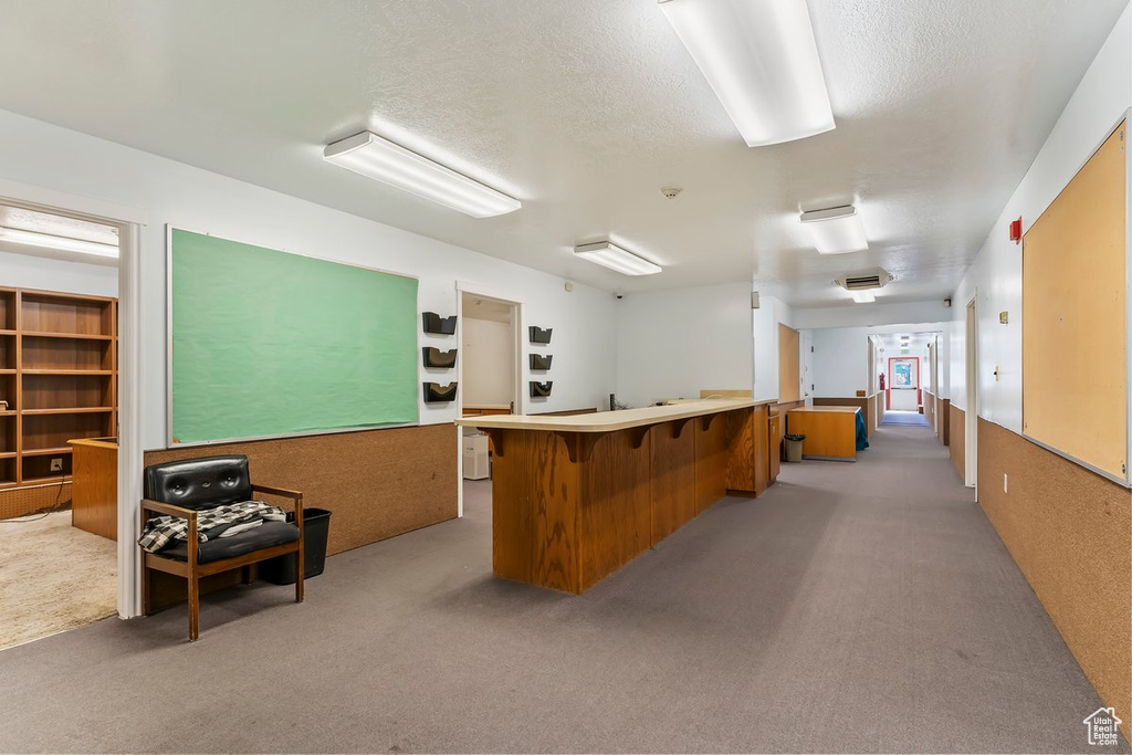 Carpeted office with a community bar and a textured ceiling