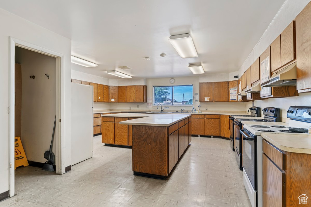 Kitchen with range with electric cooktop, brown cabinets, light flooring, and light countertops