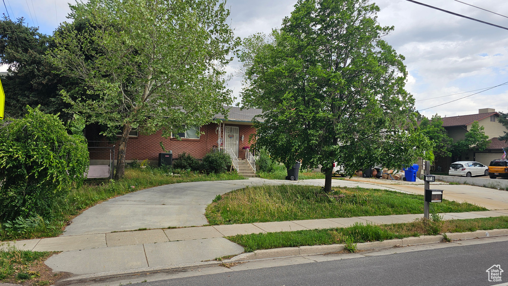 Obstructed view of property featuring concrete driveway, central air condition unit, and brick siding
