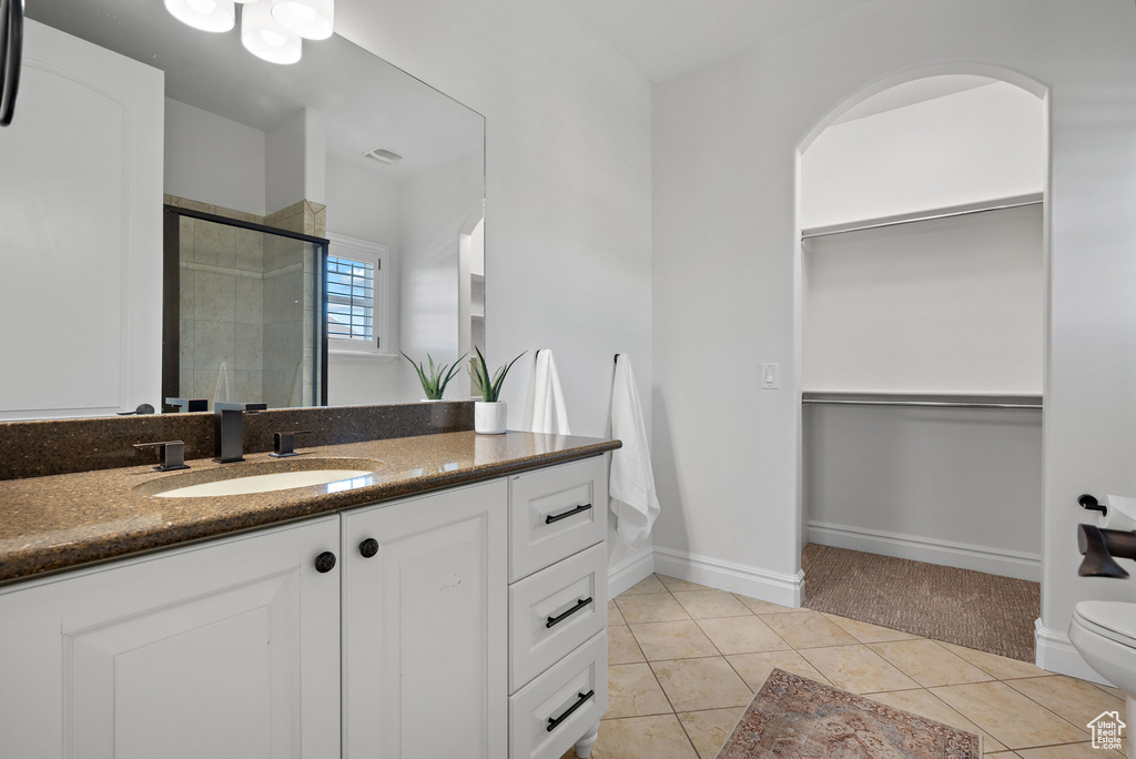 Full bath featuring a stall shower, tile patterned floors, a spacious closet, vanity, and toilet
