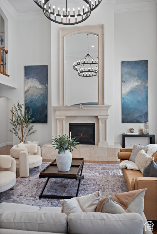 Living room with a chandelier, ornamental molding, arched walkways, and a fireplace