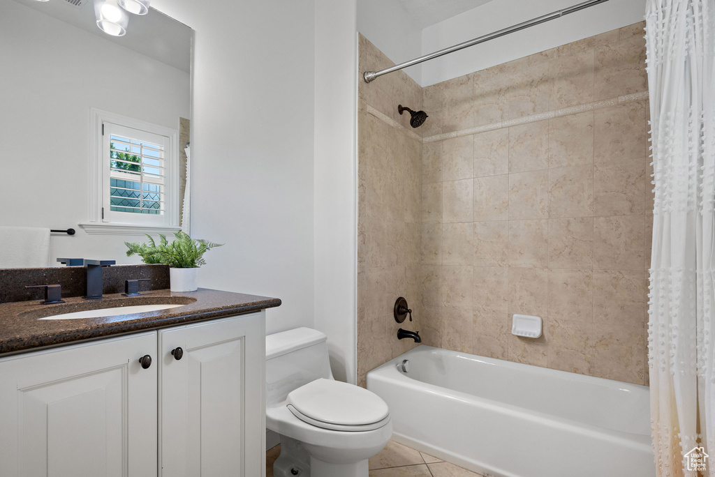 Full bathroom featuring toilet, shower / tub combo with curtain, tile patterned floors, and vanity