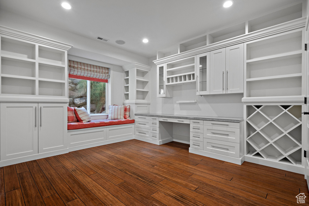 Unfurnished office featuring built in desk, dark wood-type flooring, and recessed lighting