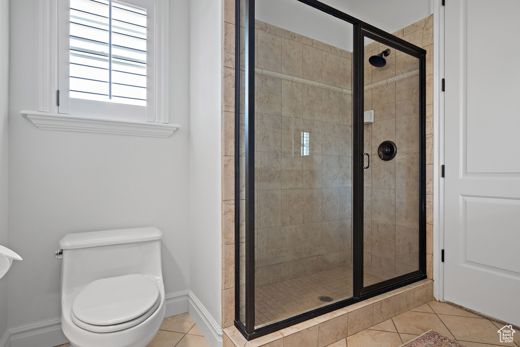 Bathroom with tile patterned floors, a shower stall, baseboards, and toilet