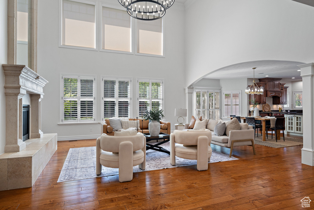 Living area with a chandelier, arched walkways, a premium fireplace, wood-type flooring, and a high ceiling