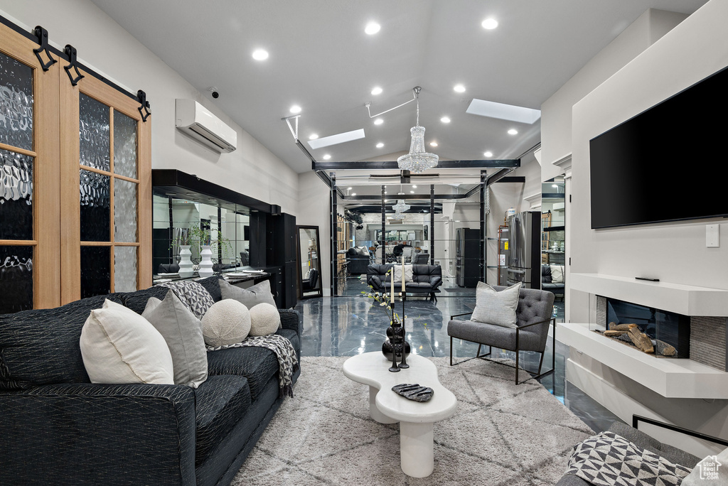 Living area with an AC wall unit, recessed lighting, vaulted ceiling, and a skylight