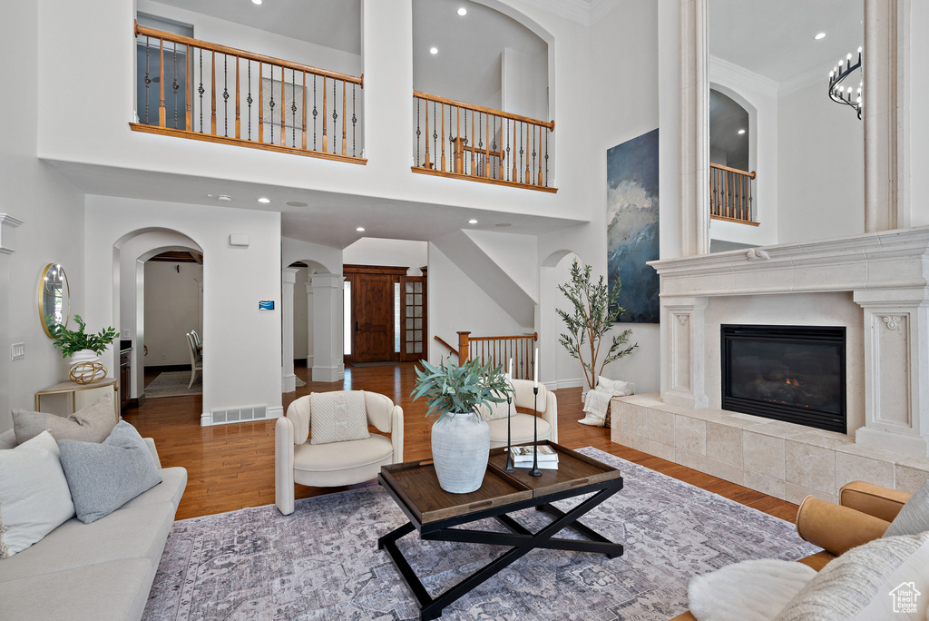 Living room with arched walkways, wood finished floors, recessed lighting, baseboards, and a fireplace