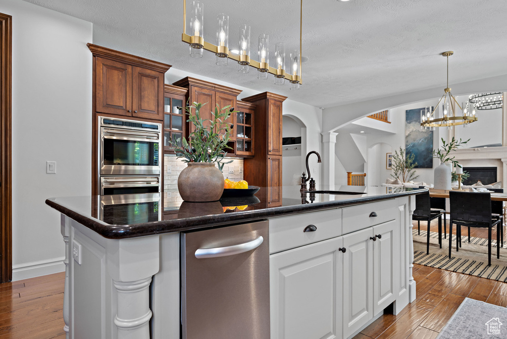 Kitchen featuring a sink, arched walkways, a chandelier, double oven, and hardwood / wood-style flooring