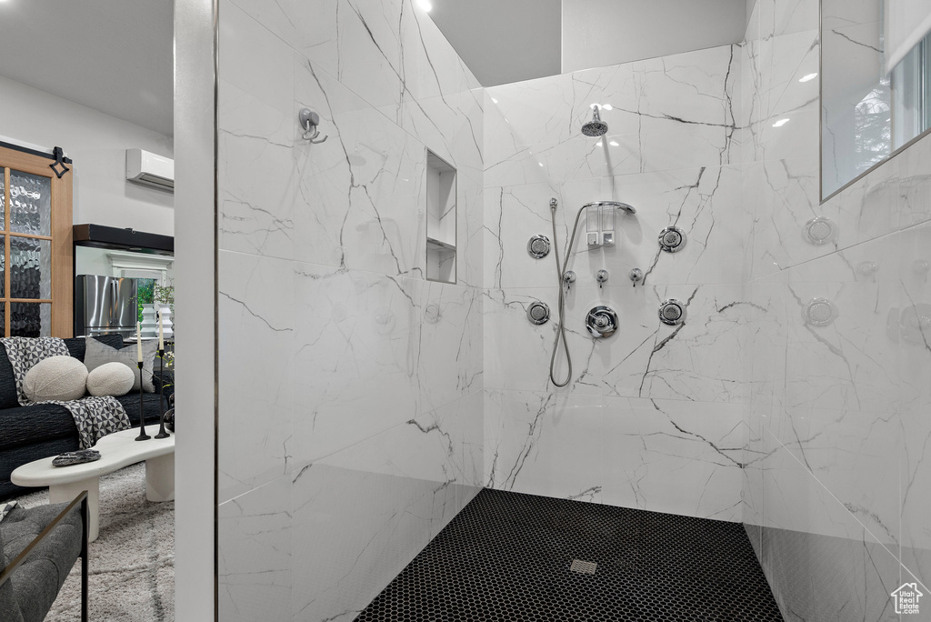 Full bath with a wall mounted air conditioner and a marble finish shower