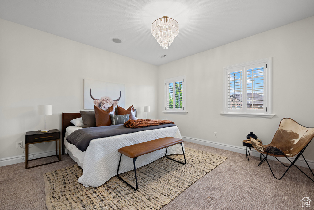 Carpeted bedroom featuring a chandelier and baseboards