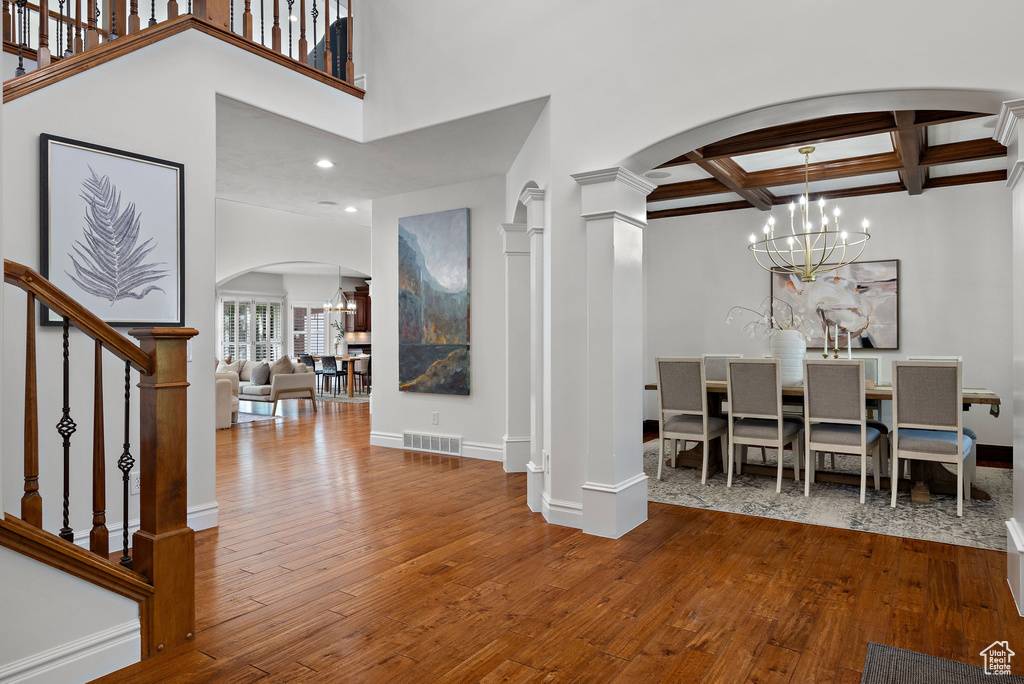 Foyer entrance featuring arched walkways, baseboards, wood-type flooring, beamed ceiling, and coffered ceiling