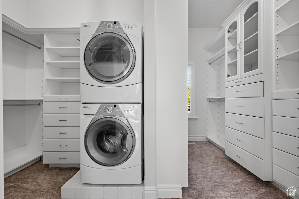 Clothes washing area with estacked washer and dryer and dark carpet