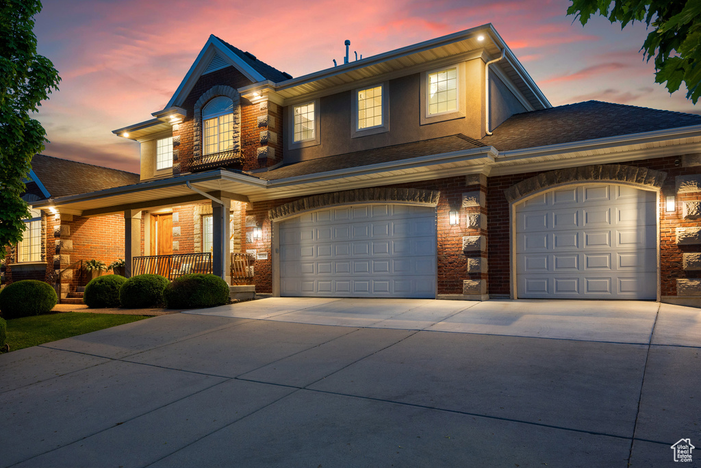 View of front of house featuring brick siding, covered porch, concrete driveway, and a garage