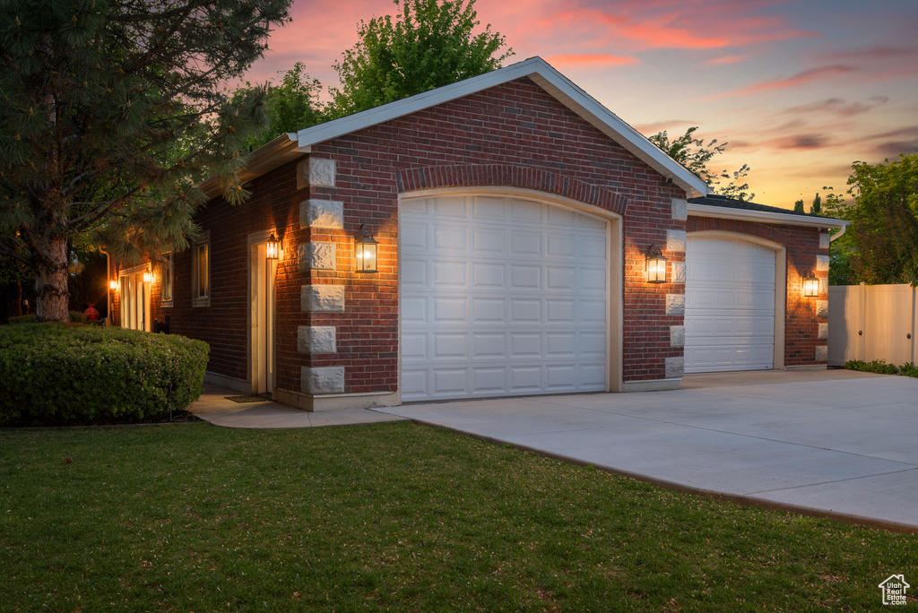 View of front of house featuring brick siding, a front yard, driveway, and an attached garage