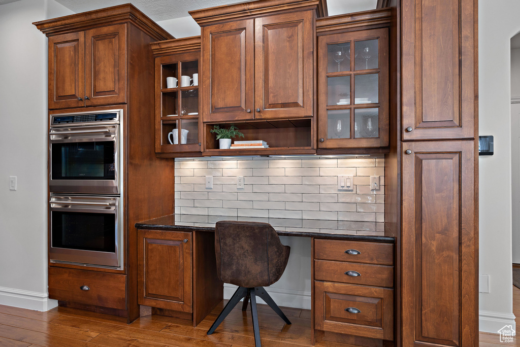 Office area featuring built in study area, wood finished floors, and baseboards