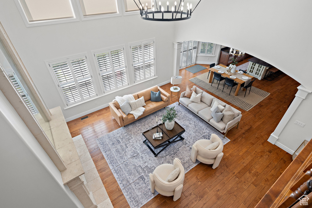 Living area featuring decorative columns, arched walkways, a chandelier, hardwood / wood-style floors, and plenty of natural light