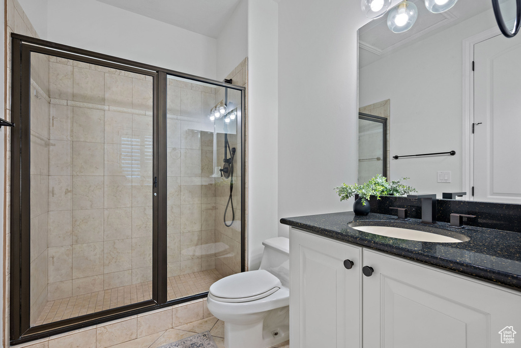 Full bathroom featuring a stall shower, toilet, vanity, and tile patterned flooring