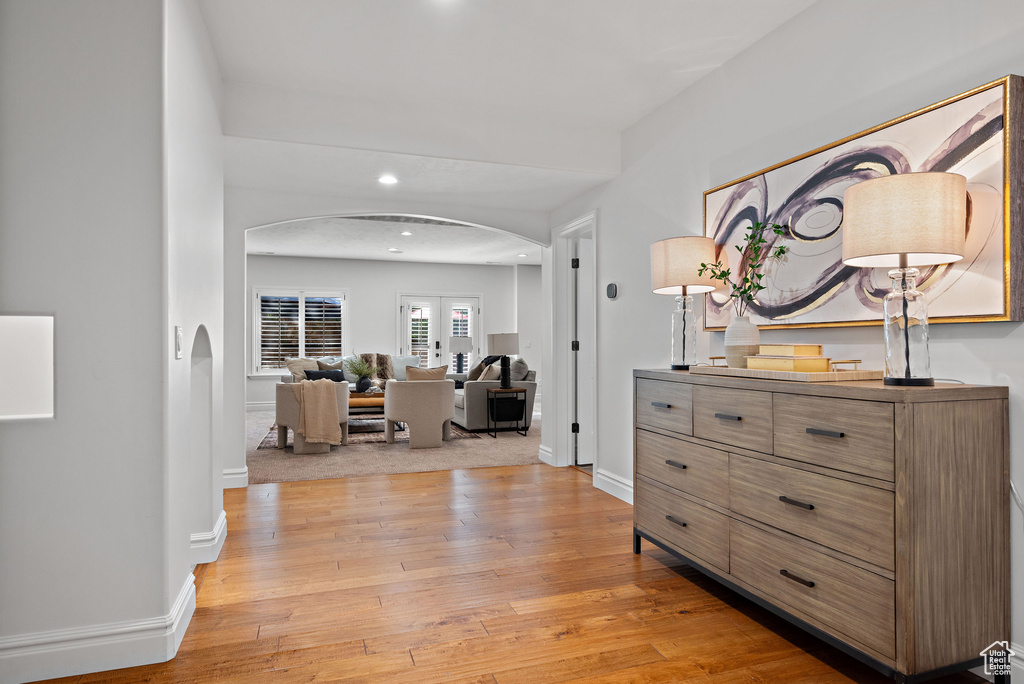 Corridor with arched walkways, light wood-type flooring, baseboards, and recessed lighting