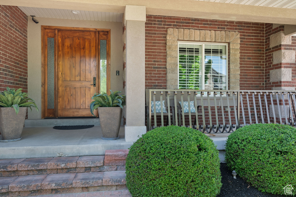 Entrance to property featuring brick siding and covered porch