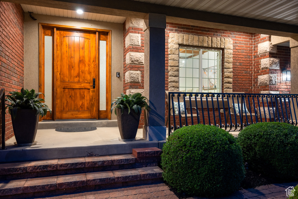 Doorway to property featuring covered porch and brick siding