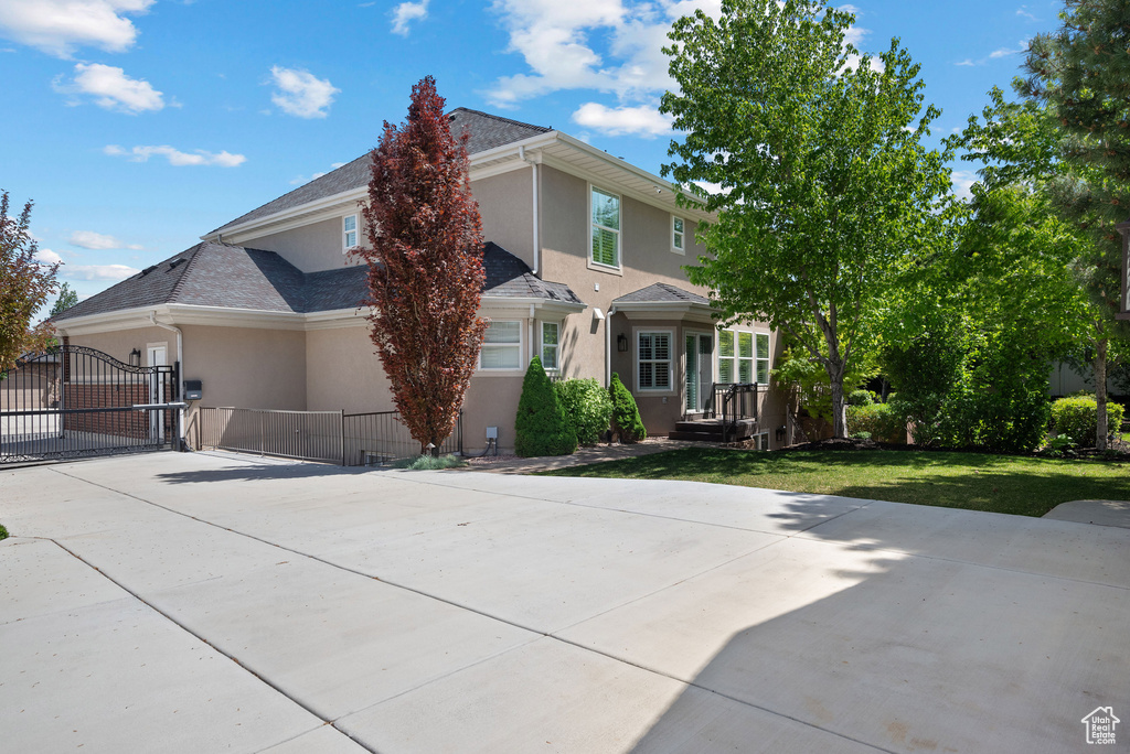 View of front of house with stucco siding, driveway, and a gate