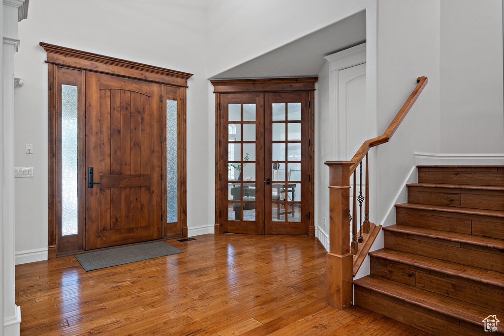 Entrance foyer with french doors, wood finished floors, plenty of natural light, and stairway