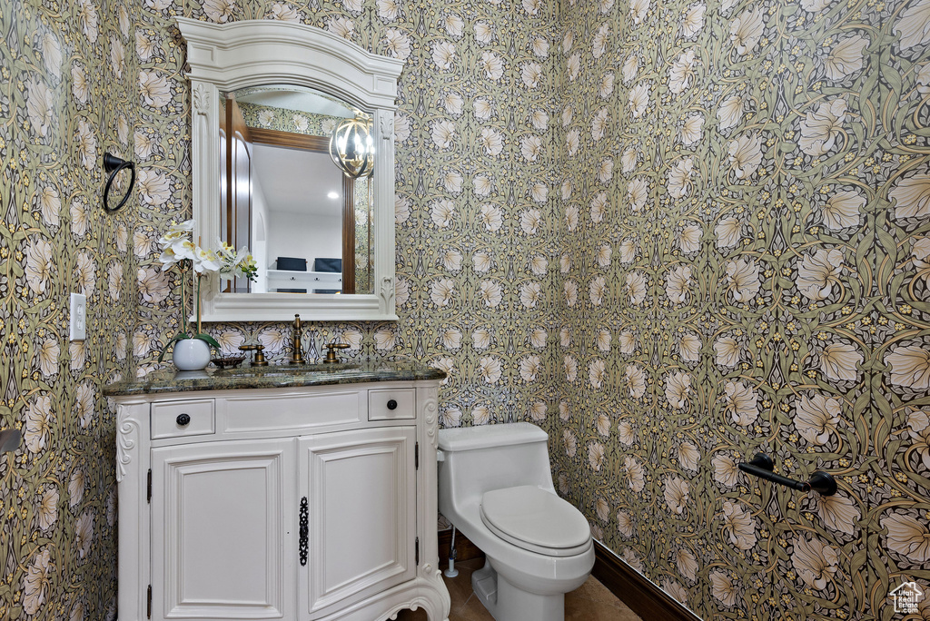 Bathroom featuring vanity, toilet, and wallpapered walls