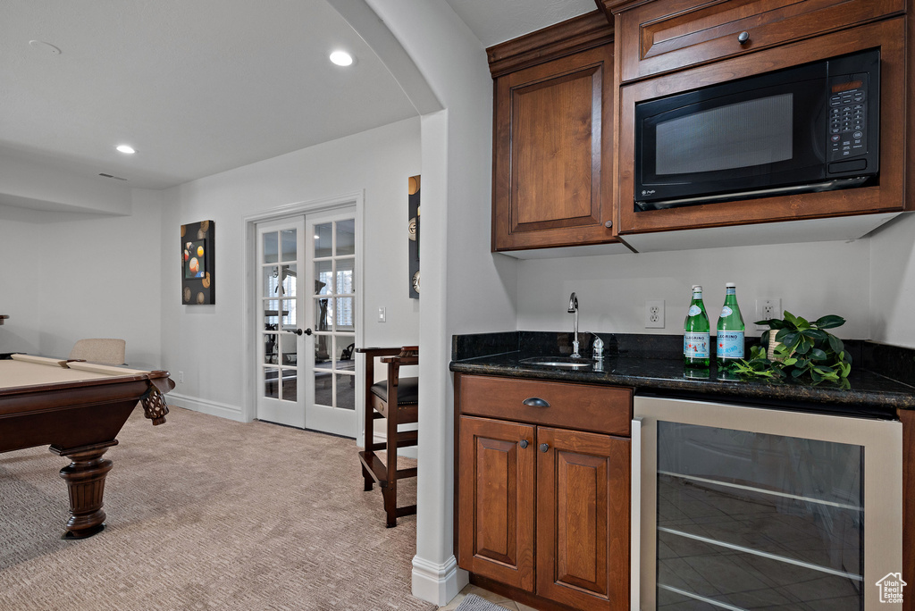 Indoor wet bar with beverage cooler, black microwave, french doors, light colored carpet, and recessed lighting