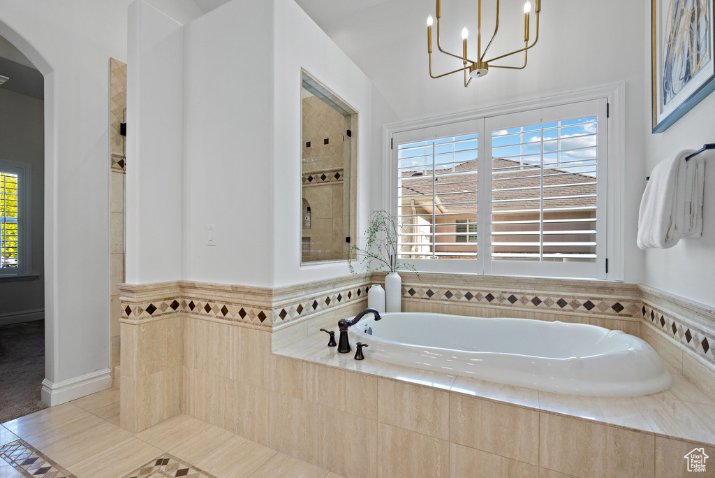 Bathroom with a chandelier, a garden tub, a tile shower, and tile patterned flooring