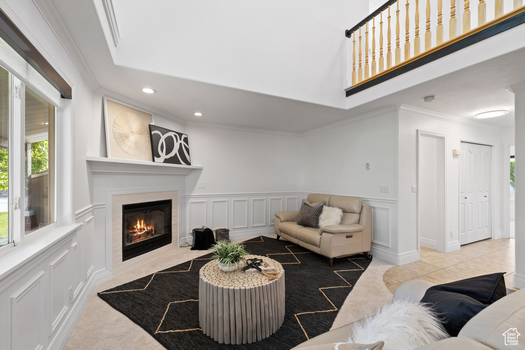 Living area featuring ornamental molding, a decorative wall, a fireplace, recessed lighting, and wainscoting
