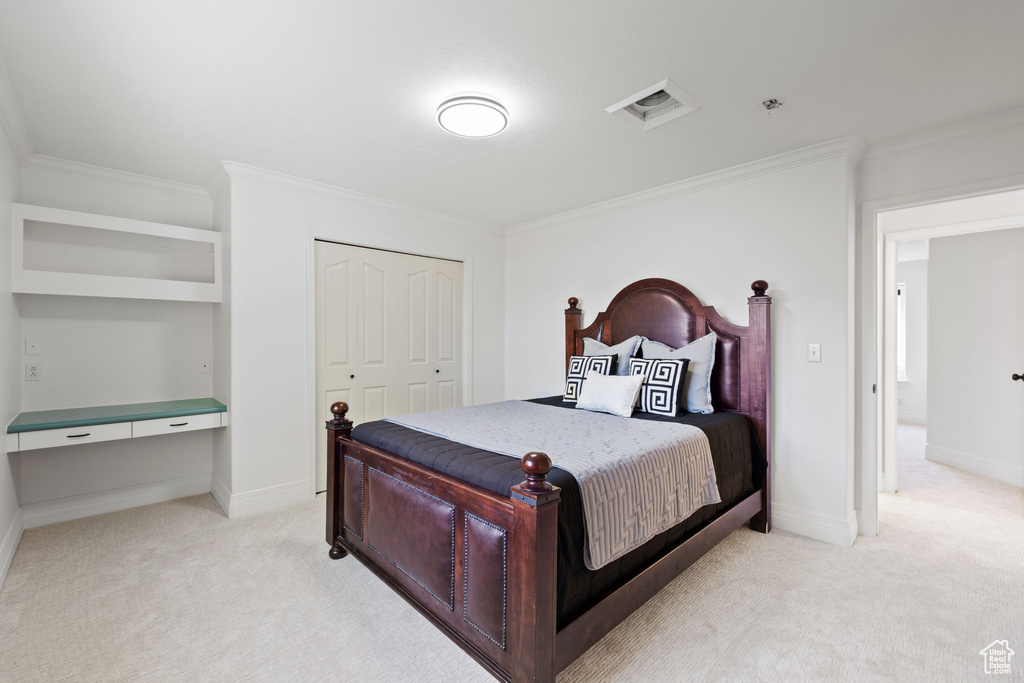 Bedroom with light colored carpet, crown molding, a closet, and baseboards