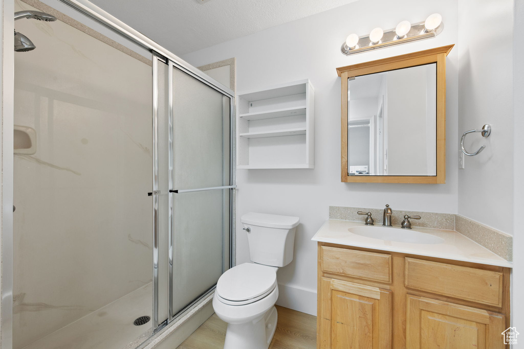 Bathroom with a shower stall, toilet, vanity, and wood finished floors