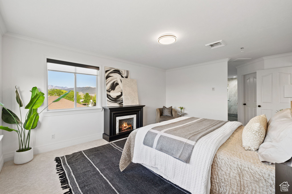 Bedroom with crown molding, carpet floors, a lit fireplace, and baseboards