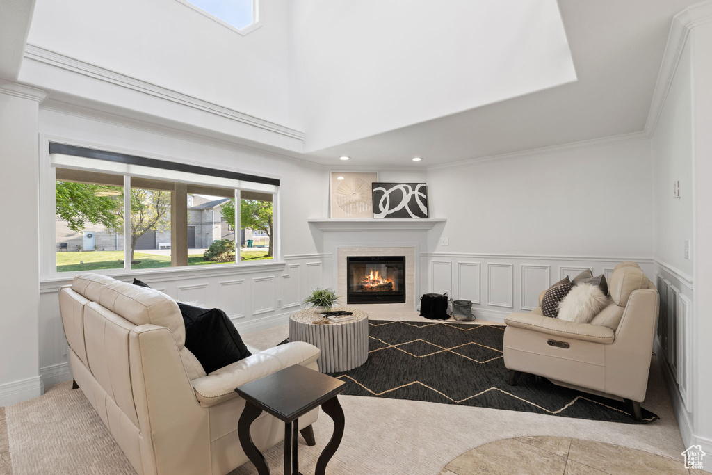 Living room featuring a glass covered fireplace, a decorative wall, healthy amount of natural light, wainscoting, and crown molding