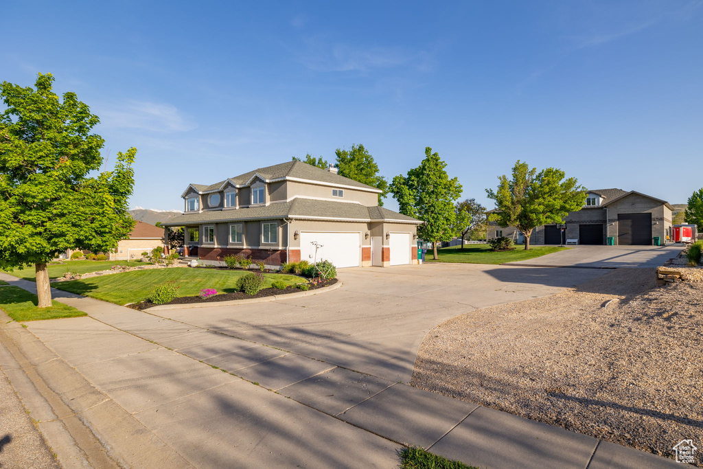 Traditional home with concrete driveway, a front yard, roof with shingles, and stucco siding