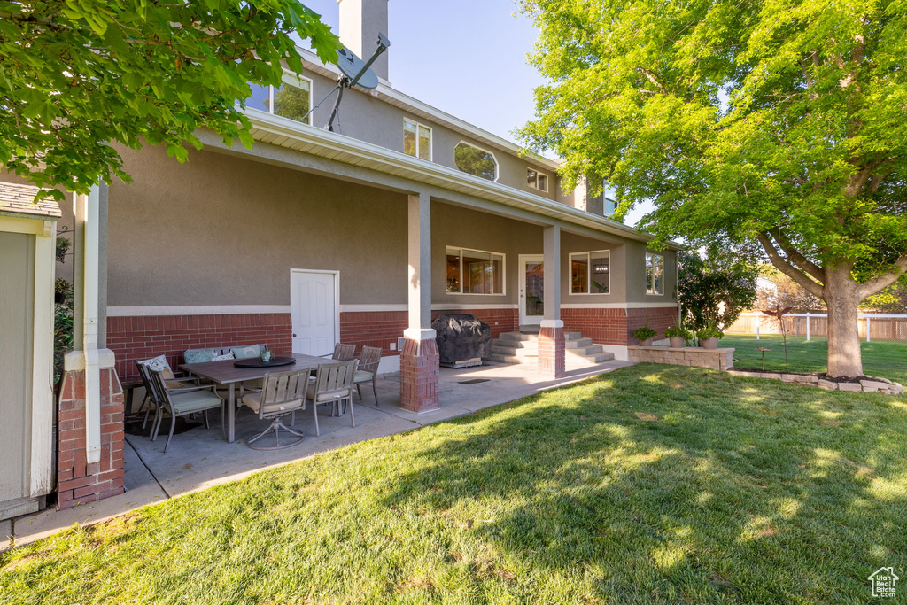 Rear view of property with brick siding, a patio, and stucco siding