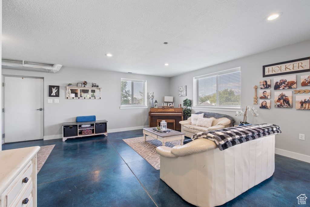 Living area with finished concrete flooring, recessed lighting, a textured ceiling, and baseboards
