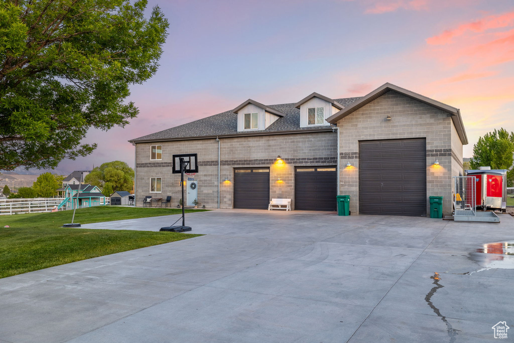 View of front facade with an attached garage, driveway, a shingled roof, and stone siding