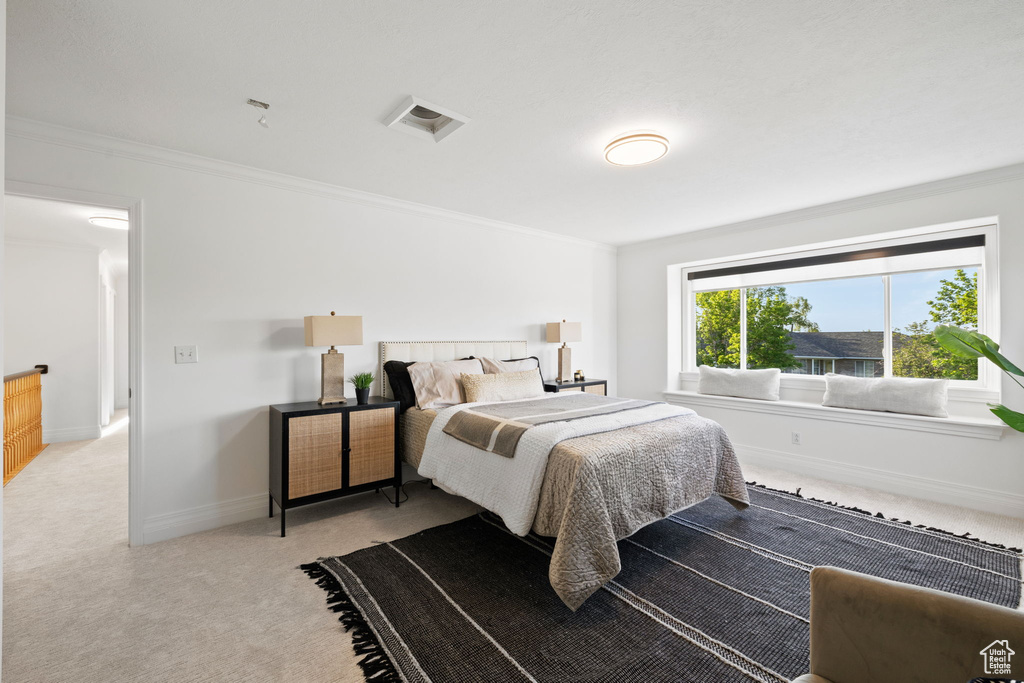 Bedroom featuring light carpet, ornamental molding, and baseboards