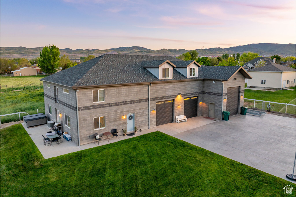 Back of property featuring concrete driveway, a garage, a mountain view, and a patio