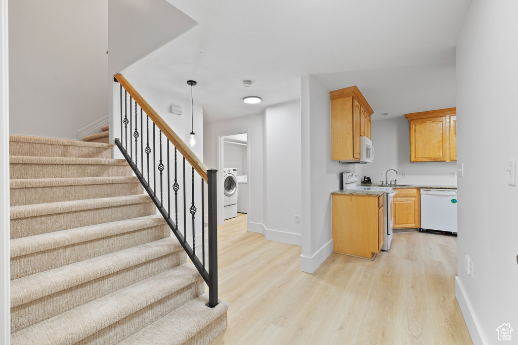 Staircase with baseboards, wood finished floors, and washer / clothes dryer